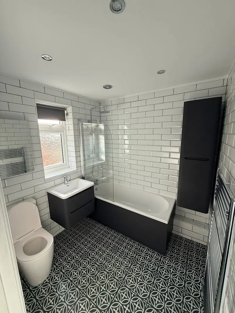 Renovated bathroom with white metro tiles, a black and white patterned floor and a charcoal vanity unit