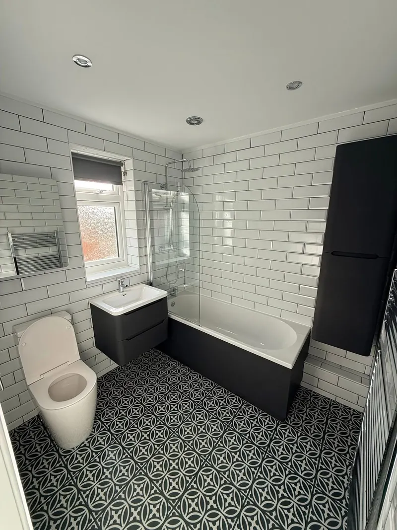 Renovated bathroom with white metro tiles, a charcoal bath panel and a tall charcoal storage unit