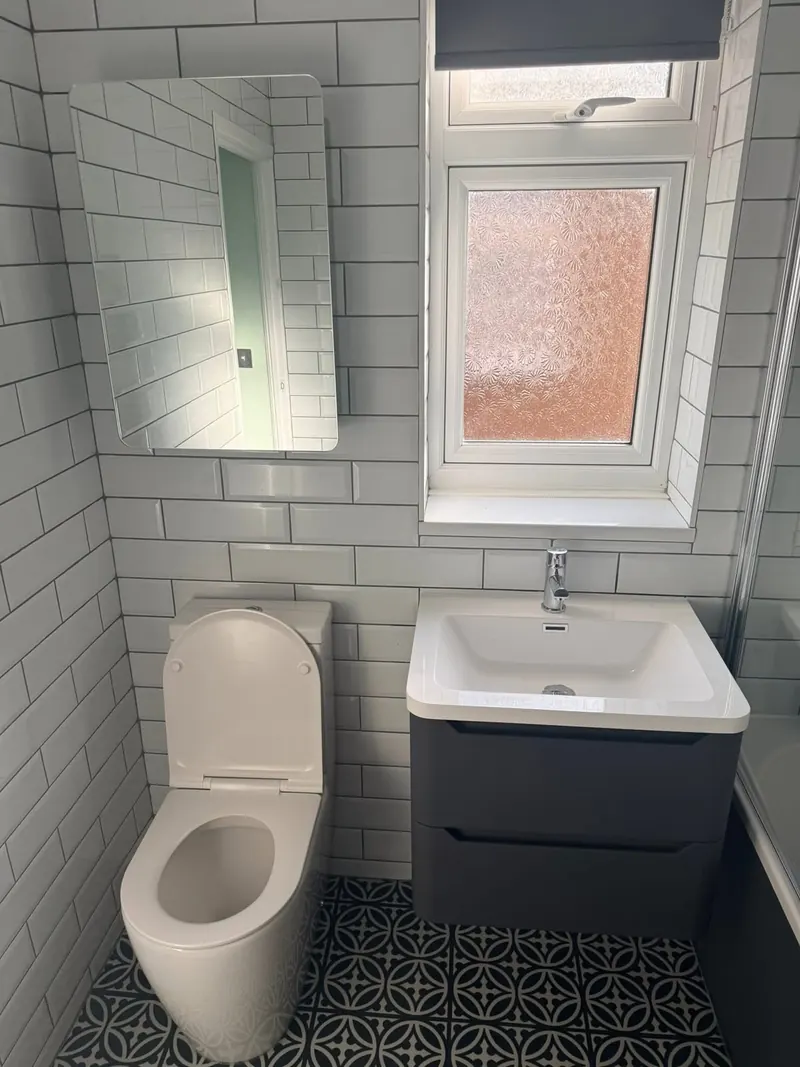 Toilet and wall-hung charcoal vanity unit under the window, with white metro tiles