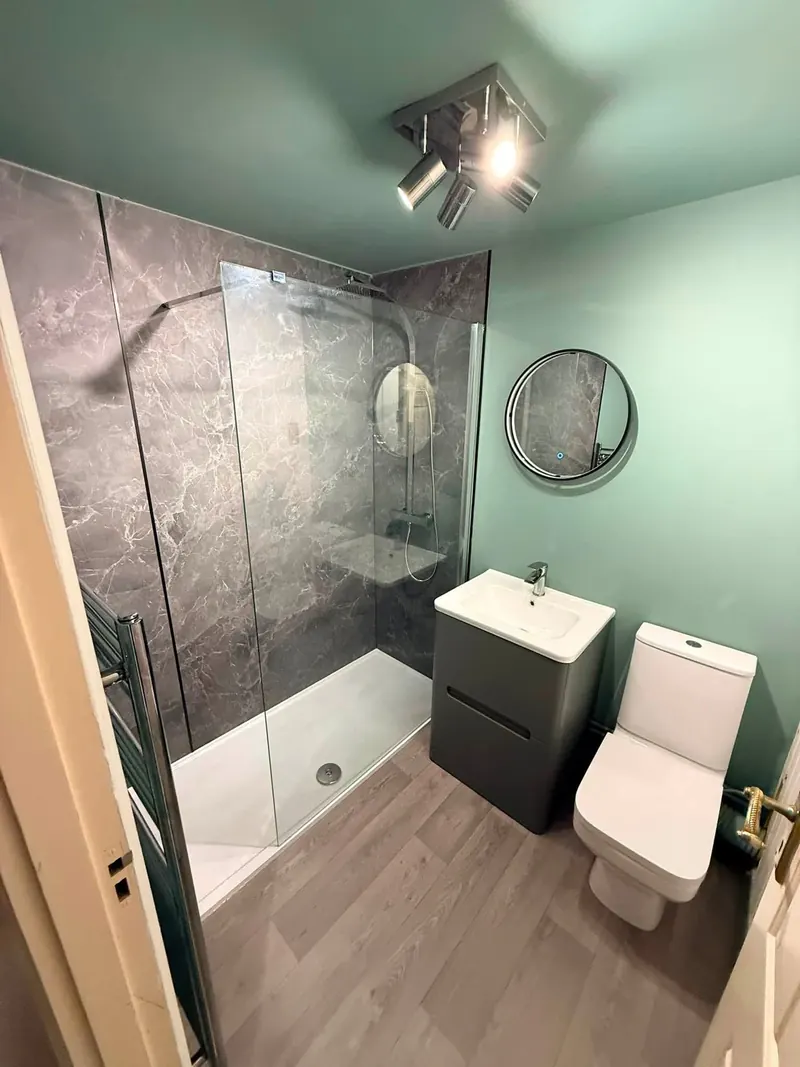 Renovated shower room with a walk-in shower, grey marble-effect panels and green walls