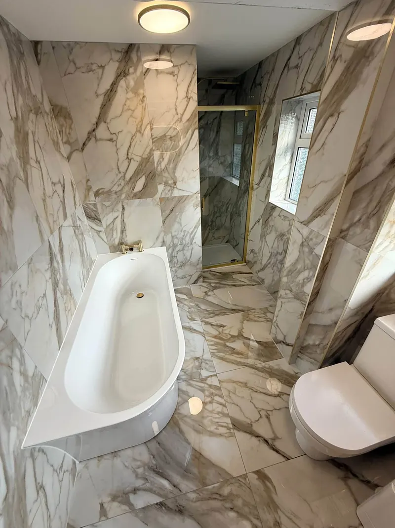 Finished bathroom with marble-effect tiles, a back-to-wall bath and a brass-framed shower