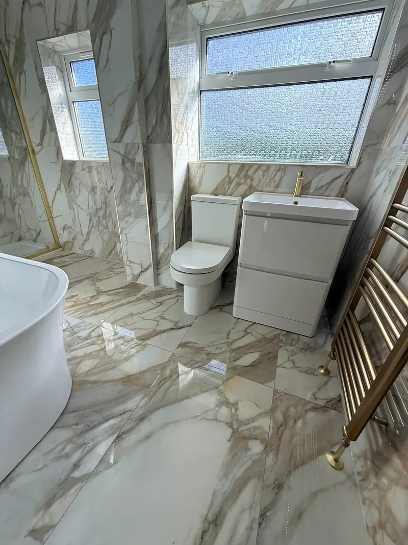 Marble-effect floor and walls with a white vanity unit, toilet and brass towel rail