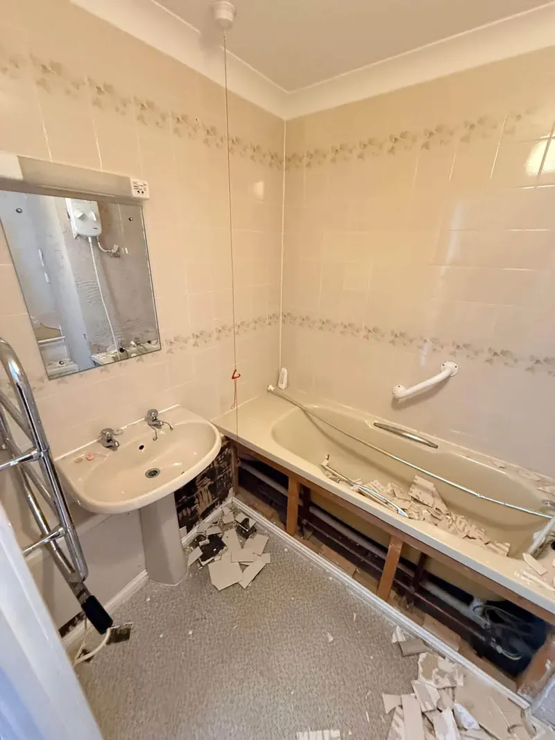 Bathroom being stripped out, with the old bath and basin still in place