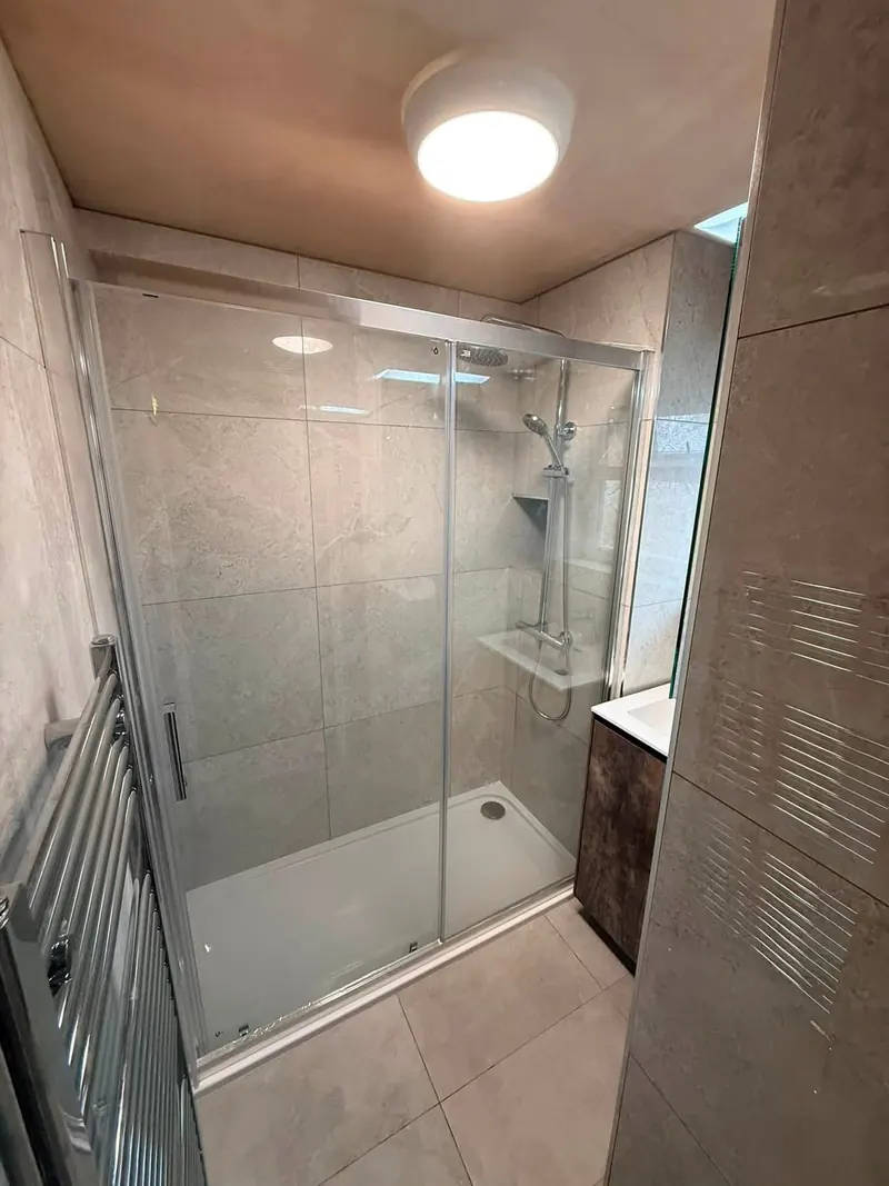 New shower room with a sliding-door shower enclosure, stone-effect tiles and a rainfall shower