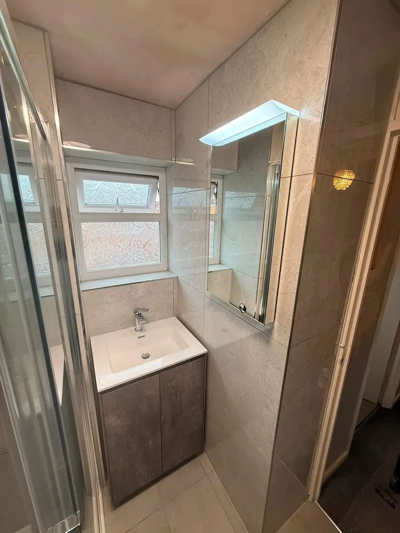 Vanity unit under the window with an LED mirror and stone-effect tiles