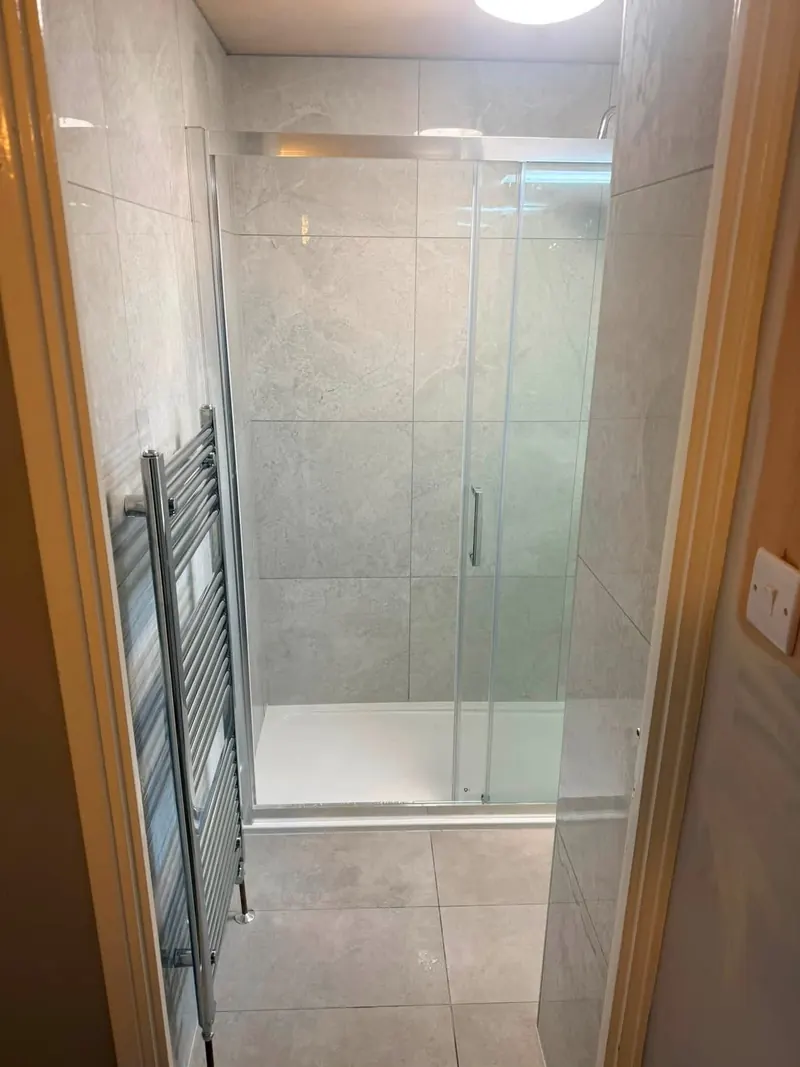 Shower enclosure seen from the door, with a chrome towel rail and stone-effect floor tiles