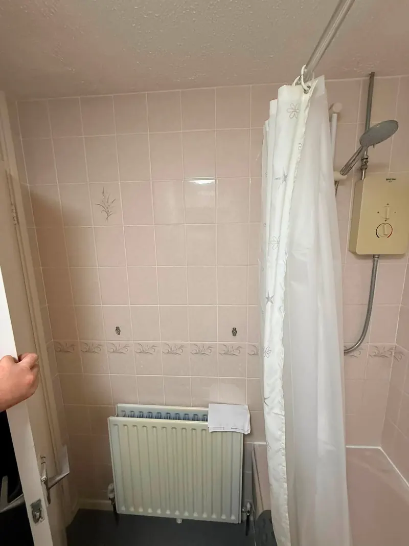Pink tiled wall with a radiator next to the bath