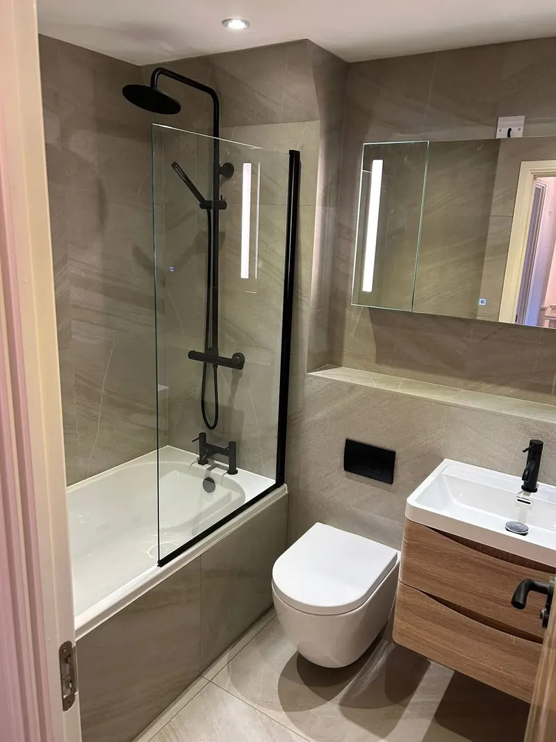 Bath, wall-hung toilet and vanity unit with an LED mirror above, seen from the door