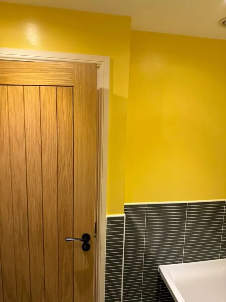 Yellow walls and dark grey strip tiles next to an oak door