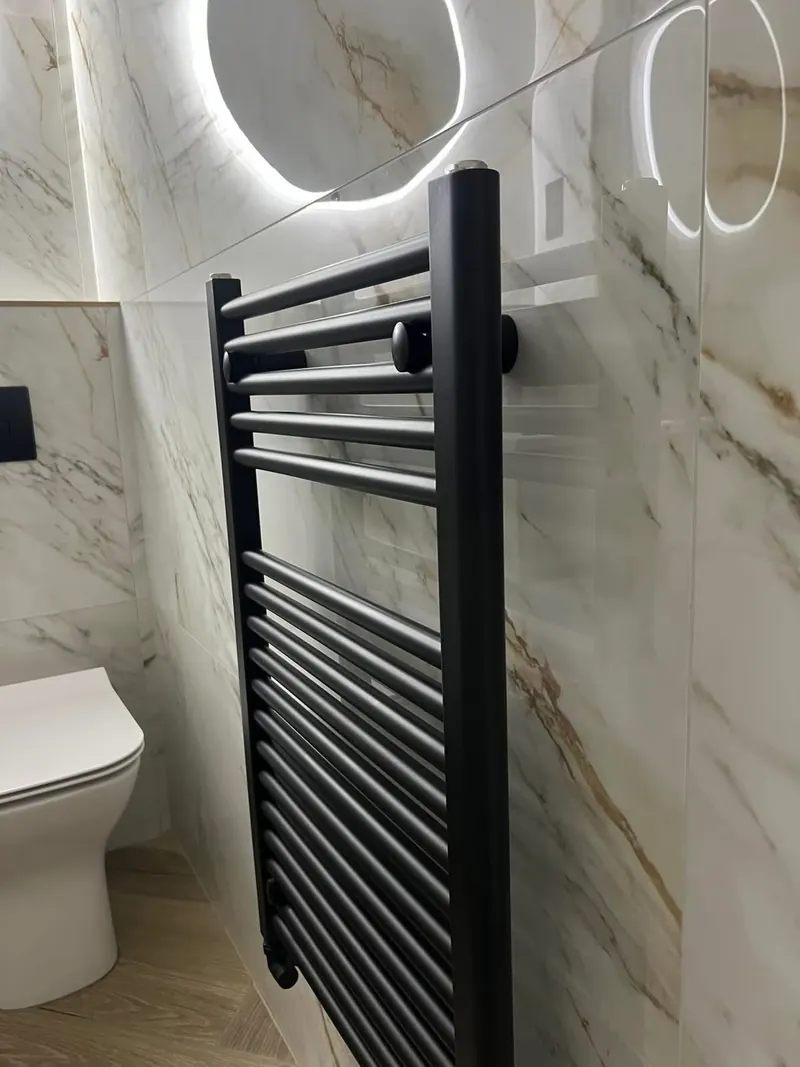 Black towel rail on gold-veined marble-effect tiles