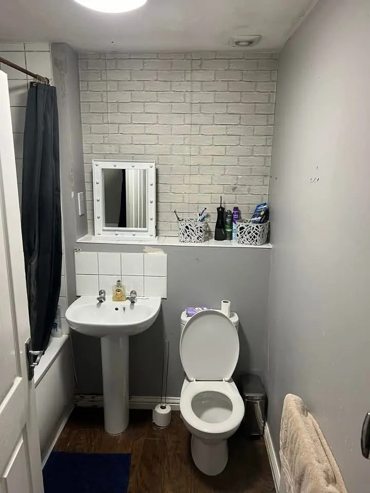 Bathroom before, with brick-effect wallpaper, a pedestal basin and a toilet