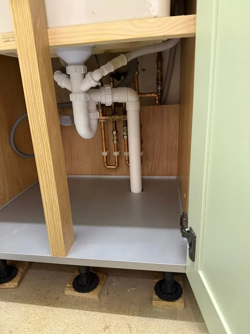 Copper pipework, isolation valves and the sink waste in the cupboard under a new kitchen sink