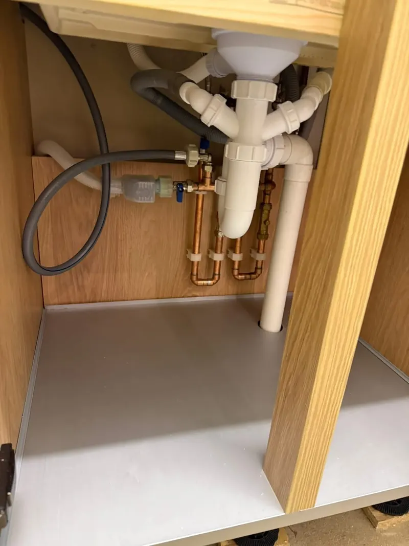 Pipework under the kitchen sink, with isolation valves and the appliance connections