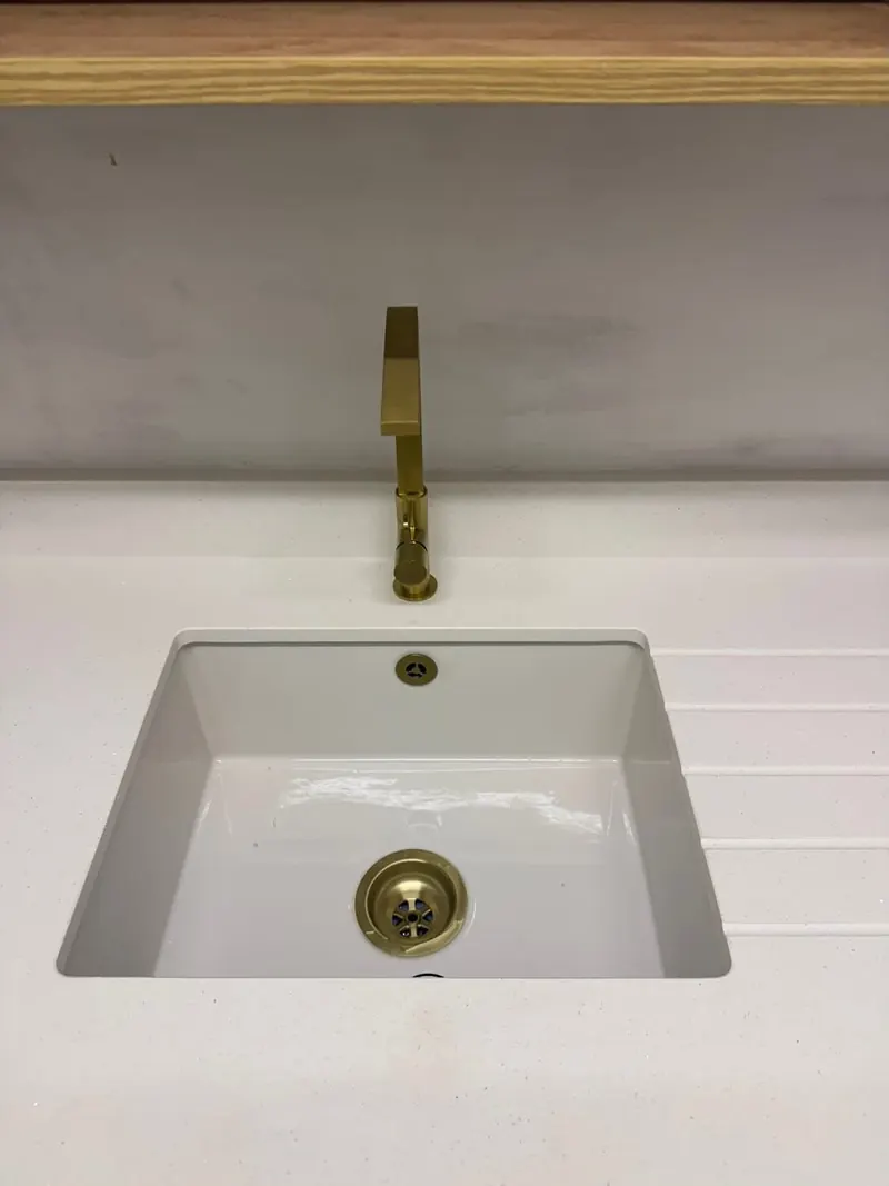 Close-up of the kitchen sink with its brushed brass tap and waste